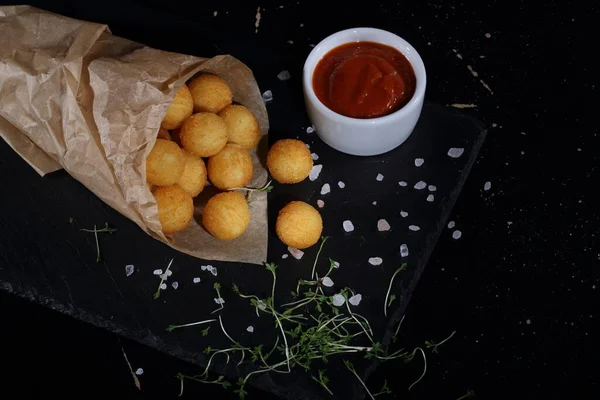 Peynirli Patates Topları Siyah Arka Planda Kağıt Torba Dolduruyor — Stok fotoğraf