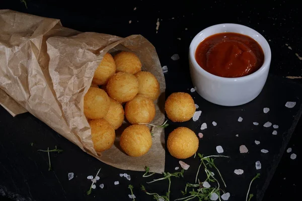 Peynirli Patates Topları Siyah Arka Planda Kağıt Torba Dolduruyor — Stok fotoğraf