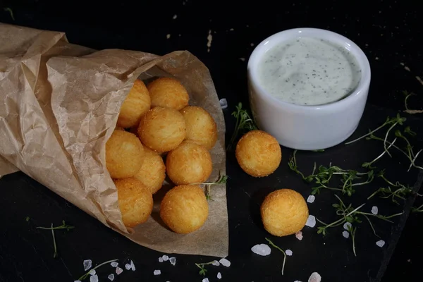 Peynirli Patates Topları Siyah Arka Planda Kağıt Torba Dolduruyor — Stok fotoğraf