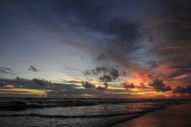 Sahilde dramatik bir öğleden sonra gökyüzü, gel-git dalgalarıyla yanan gökyüzü güzellik ve korkunç bir şey arasında huzursuz bir atmosfer getiriyor..