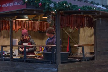 Brno, Çek Cumhuriyeti-Aralık 16,2018: Kadın ve erkek Satılık sosis Noel pazarı üzerinde 16 Aralık 2018 Özgürlük Meydanı'nda, Brno, Çek Cumhuriyeti 