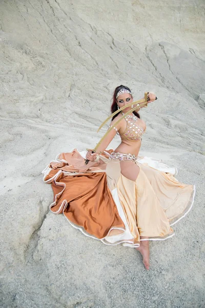 若い美しい白人女性ベリー ダンサー砂漠の剣でポーズ ストック画像
