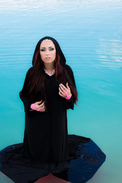 Young beautiful Caucasian woman posing in abaya in blue water — Stock Photo, Image