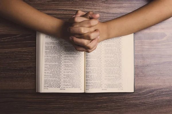 Orando con las manos con la Santa Biblia — Foto de Stock