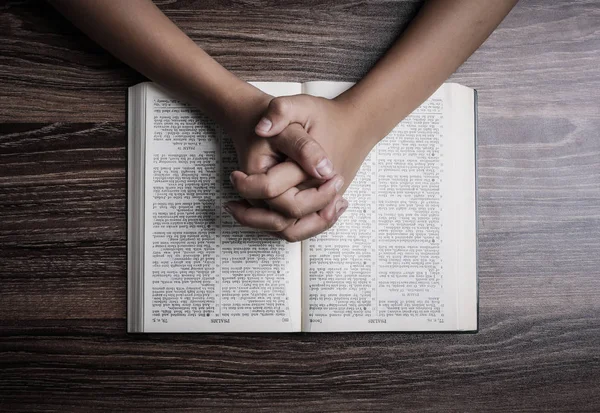 Orando mãos com a Bíblia Sagrada — Fotografia de Stock