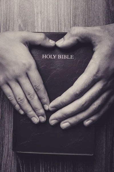 Sacra Bibbia con le mani a forma di cuore — Foto Stock
