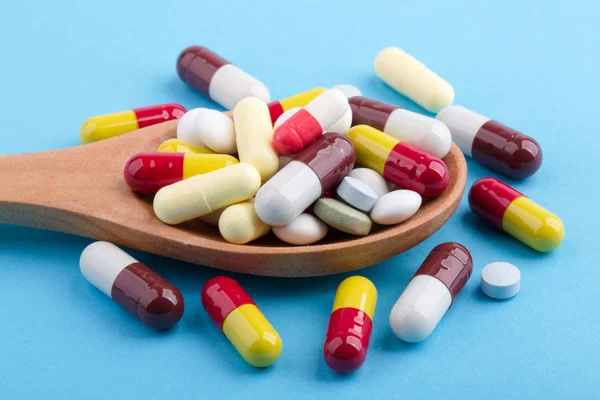 Comprimidos de medicina e cápsulas em colher de madeira — Fotografia de Stock