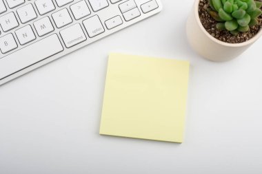 Bilgisayar klavyesi ve diğer ofis malzemeleriyle dolu beyaz ofis masası. Kopyalama alanı olan üst görünüm, düz yatay.