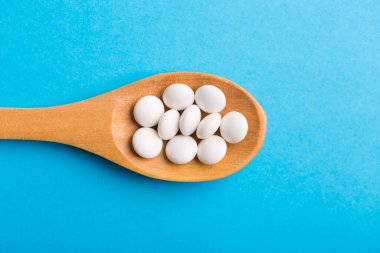 Eczane temalı, mavi arka planda ilaçlı kaşık.