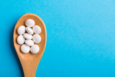 Eczane temalı, mavi arka planda ilaçlı kaşık.