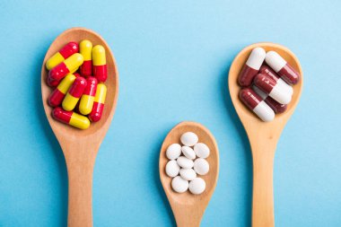 Eczane temalı, mavi arka planda ilaçlı kaşık.