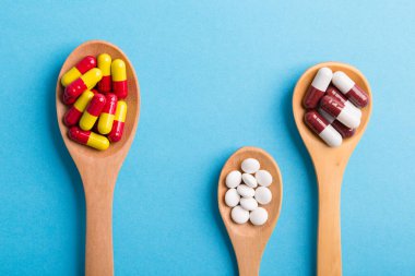 Eczane temalı, mavi arka planda ilaçlı kaşık.