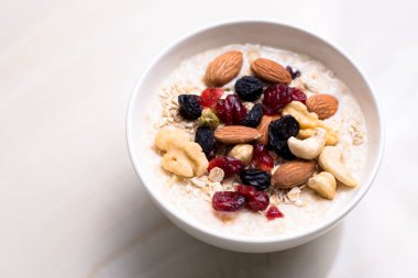Sağlıklı kahvaltı. Taze granola, yoğurt sütlü müsli ve masa arkasında fındık. Kopyalama alanı olan üst görünüm.