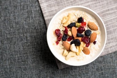 Sağlıklı kahvaltı. Taze granola, yoğurt sütlü müsli ve masa arkasında fındık. Kopyalama alanı olan üst görünüm.
