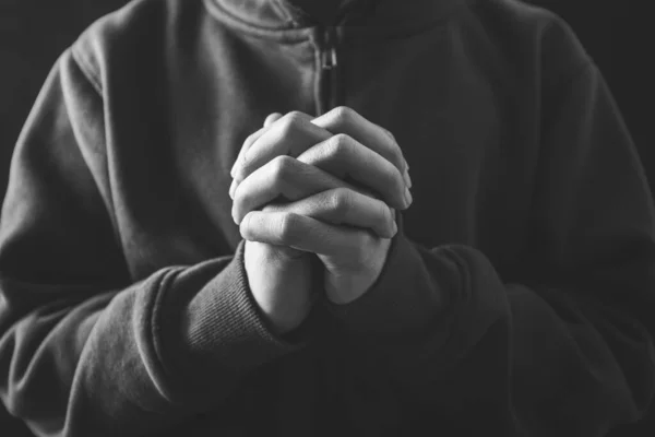 Christian faith towards God concept, Asian man christians worship and pray in church. Praying in dark black background.