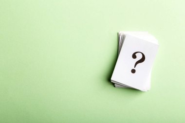 Yığınlanmış soru işaretleri, kavramsal bir resimde kopyalama alanı olan yeşil bir arkaplanda düzenlenmiş beyaz kağıt veya tabelalara basılmıştır..