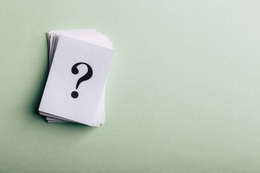 Yığınlanmış soru işaretleri, kavramsal bir resimde kopyalama alanı olan yeşil bir arkaplanda düzenlenmiş beyaz kağıt veya tabelalara basılmıştır..