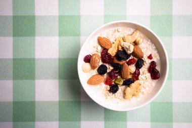 Sağlıklı kahvaltı. Taze granola, yoğurt sütlü müsli ve masa arkasında fındık. Kopyalama alanı olan üst görünüm.