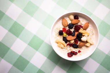 Sağlıklı kahvaltı. Taze granola, yoğurt sütlü müsli ve masa arkasında fındık. Kopyalama alanı olan üst görünüm.
