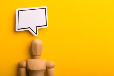 Boş konuşma baloncuğu ve sarı arkaplanda kopyalama alanı olan ahşap adam ile düşünme kavramı.