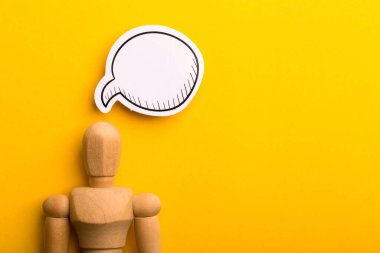 Boş konuşma baloncuğu ve sarı arkaplanda kopyalama alanı olan ahşap adam ile düşünme kavramı.