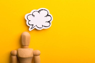 Boş konuşma baloncuğu ve sarı arkaplanda kopyalama alanı olan ahşap adam ile düşünme kavramı.