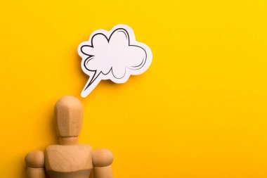 Boş konuşma baloncuğu ve sarı arkaplanda kopyalama alanı olan ahşap adam ile düşünme kavramı.