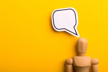 Boş konuşma baloncuğu ve sarı arkaplanda kopyalama alanı olan ahşap adam ile düşünme kavramı.