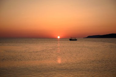 Bir balıkçı teknesi şafakta denize açılır.