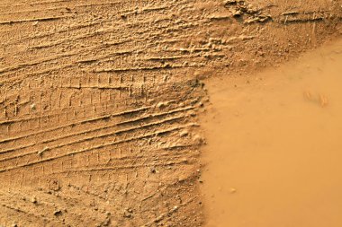 çamur, su birikintisi ve tekerlek izleri yakın plan, arka plan