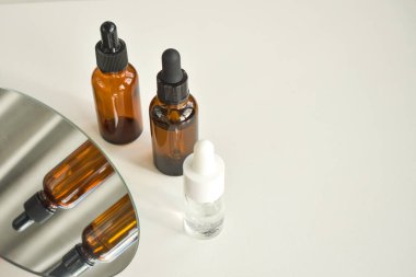 Beyaz bir masadaki kahverengi cam şişelerde kaplıca malzemeleri. Güzellik blogcusu, salon terapisi, markalaşma düzeni, minimalizm konsepti. Üst görünüm, alanı kopyala