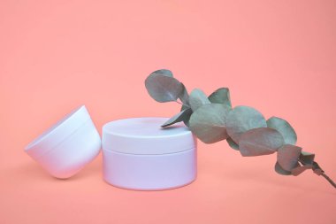 Yuvarlak, beyaz, plastik kozmetik kavanozu, pembe arka planda izole edilmiş düzen..