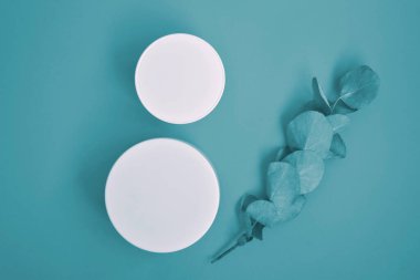 Yuvarlak, beyaz, plastik kozmetik kavanozu, mavi arkaplanda izole edilmiş düzen.