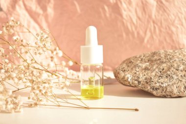 Doğal bir arka planı olan beyaz bir masada cam bir şişede gerekli kozmetik yağı şişeleri. Aromaterapi yağı, doğal kozmetik konsepti. Metin için boşluk.