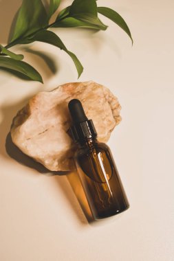 Doğal bej arka planda doğal kozmetik yağları. Taşlarının ve bitki yapraklarının dekoru var. Yüz ve vücut için eko kozmetik ve ilaç.