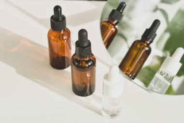 Beyaz bir masadaki kahverengi cam şişelerde kaplıca malzemeleri. Güzellik blogcusu, salon terapisi, markalaşma düzeni, minimalizm konsepti. Üst görünüm, alanı kopyala