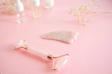 Yüzünde pembe doğal yeşim taşıyla kuvars silindirli masaj. Gouache masaj aleti, güzellik serumu yağı ile. Evde yaşlanma ve kaldırma karşıtı. Yüz masajı ve rahatlama konsepti.