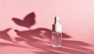 Pembe arka planı ve gölgesi olan yaşlanmayı önleyici yüz yağı. video kozmetik ve cilt bakımı kavramı.