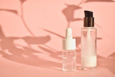 Cosmetic aromatic oils in bottles with a pipette on a pink background with shadow. The concept of natural eco-cosmetics. clipart