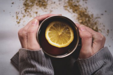 Elinde bir bardak limonla çay tutan bir kadın. Sıcak ve rahatlatıcı bir atmosfer..