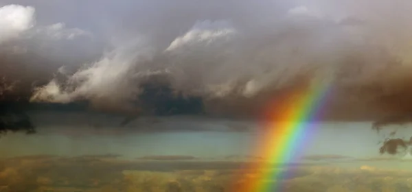 Bright rainbow after the storm in the sunset sky. Gray clouds.