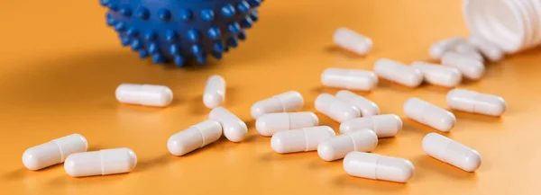İlaç hapları, haplar veya kapsüller ve sarı arka planda Corona virüsü covid-19 hücre sembolü..
