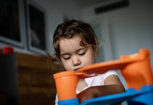 İki yaşında güzel bir kız çocuğu evde oyuncaklarıyla oynuyor.