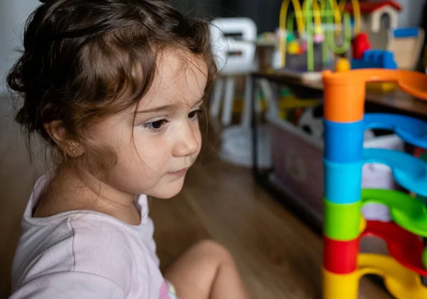 İki yaşında güzel bir kız çocuğu evde oyuncaklarıyla oynuyor.