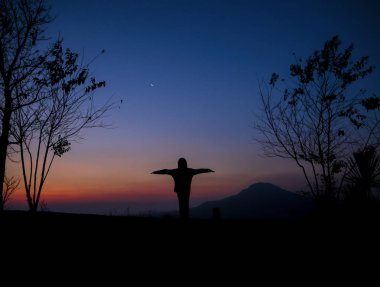 Gün doğumunda manzara nın manzarası üzerinde duran bir kadının silueti