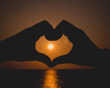 Siluet eller kalbe, gün batımı ortada.