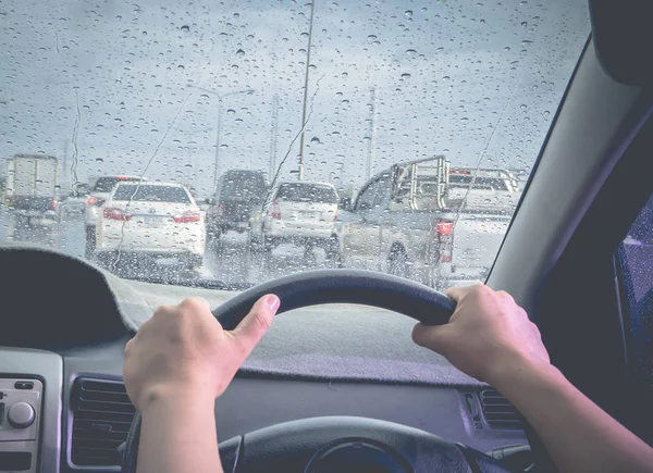 Bir yağmurlu günde sür, ön cam arabanın üstüne yağmur damlaları. (almak--dan fotoğraf sürücü el odak içinde)