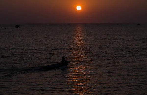 Gün doğumunda ya da batımında denizde yüzen küçük tekneler.