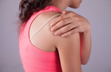 Omuz ağrısı çeken genç bir kadın..