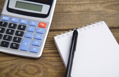 Not defteri, kalem ve hesap makinesi ahşap arkaplanda izole edilmiş..